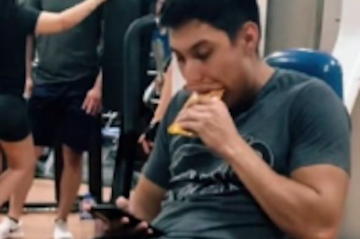 Joven come alimento para perro en el gimnasio